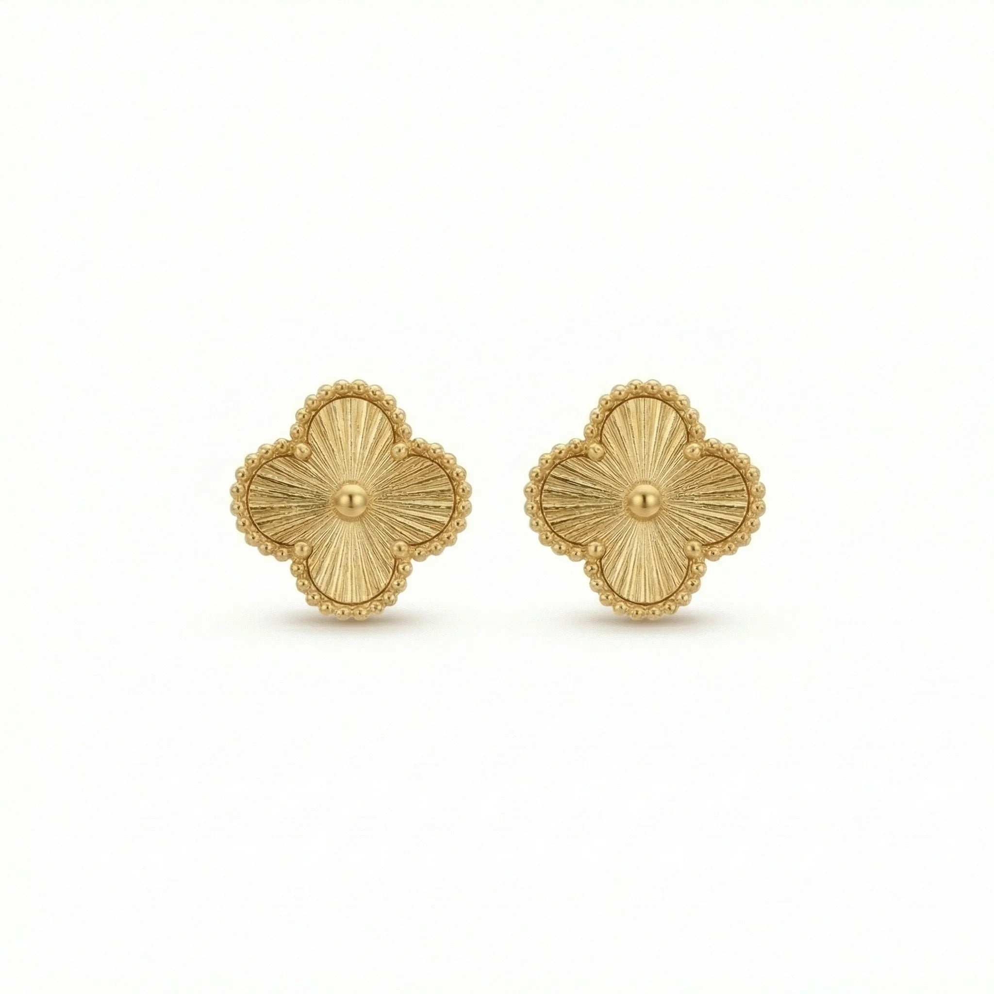 Gold clover-shaped stud earrings with embossed texture and beaded edges on white background