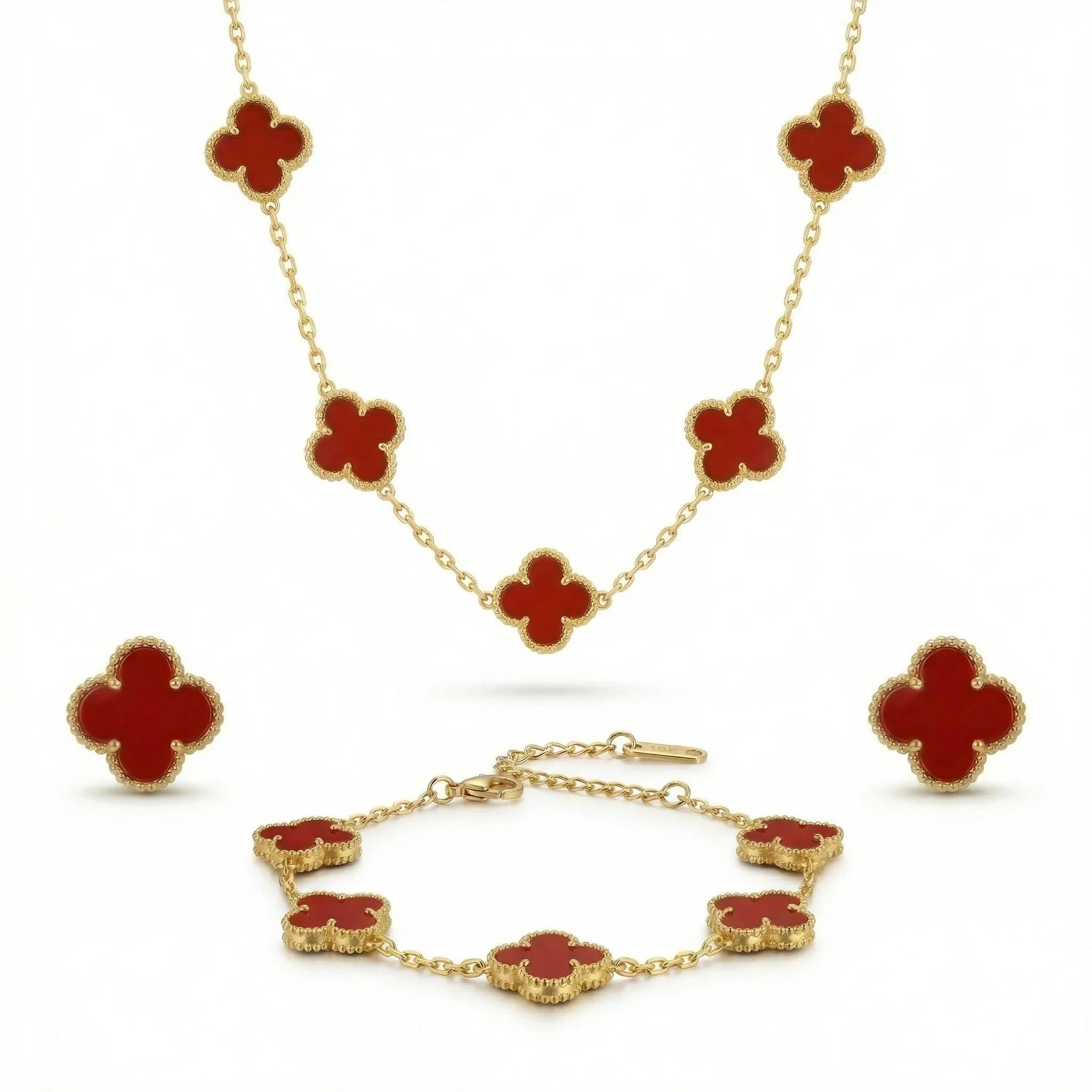 Gold jewelry set with red four-leaf clover motifs, including necklace, bracelet, and earrings.
